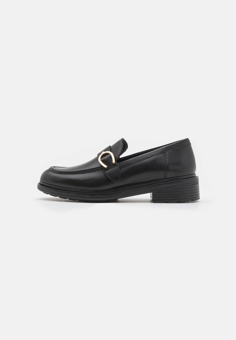 Mocasines de cuero negro con puntera redonda, una pequeña correa y una hebilla de acento en tono dorado en la parte frontal. Presentan un tacón bajo apilado.