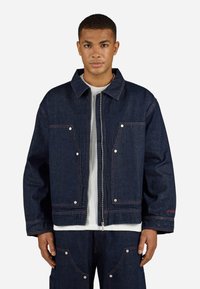 Donkerdenim jack met drukknoopsluitingen, twee borstzakken en contrasterende stiksels. Heeft een klassieke kraag en een ontspannen pasvorm.