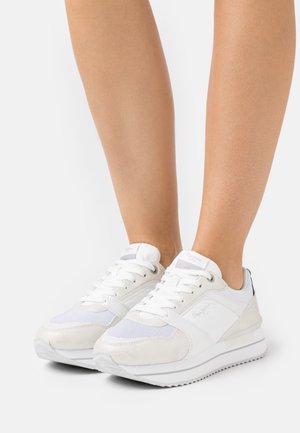 White athletic shoes with mesh and suede panels, cushioned soles, lace-up closures, and a logo on the tongue. Slim silhouette.