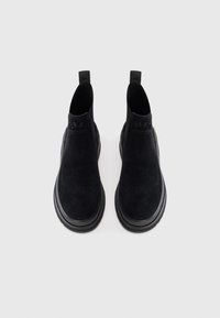 Schwarze Wildleder-Stiefeletten mit einem eleganten Design, elastischen Seitenpaneelen und einer strukturierten Gummisohle. Minimalistische Markenkennzeichnung oben.