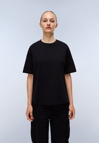 Černé bavlněné tričko s kulatým výstřihem, krátkými rukávy a decentně embosovaným logem na hrudi. Volný střih.