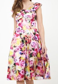 Blumenkleid mit herzförmigem Ausschnitt, verziert mit lebhaften Rosen in Pink, Gelb und Lila. Der Stoff ist glatt, hat eine taillierte Taille und einen schwingenden Rock.