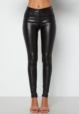 Pantaloni neri a vita alta realizzati in materiale lucido e elasticizzato; design aderente con una texture liscia e dettagli di cucitura minimi.