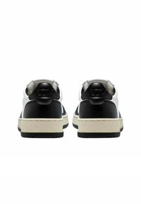 Sneaker bianco e nero in pelle liscia, con dettagli sul tallone a contrasto, suola intermedia bianca spessa e suola esterna in gomma nera strutturata.