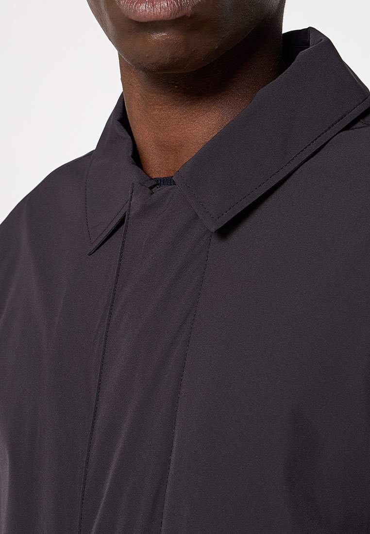 Ciemnoszara, lekką kurtka z ustrukturyzowanym kołnierzem i gładką fakturą, z widocznymi szwami wzdłuż przedniego panelu.