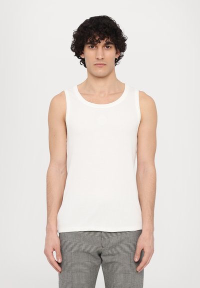 Top sin mangas de rayas blancas con cuello redondo. Combinado con pantalones de cuadros grises. Textura suave, estilo minimalista.