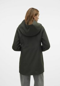 Chaqueta impermeable verde oscuro con una gran capucha, bolsillos frontales y un ajuste entallado, que muestra una textura suave y mate.