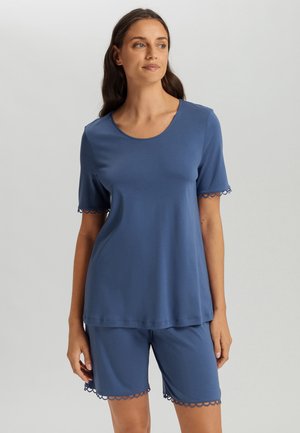 Niebieski komplet piżamowy zawiera bluzkę z krótkim rękawem i okrągłym dekoltem oraz ozdobnym falbaniastym wykończeniem rękawów i spodenek. Miękka struktura materiału.