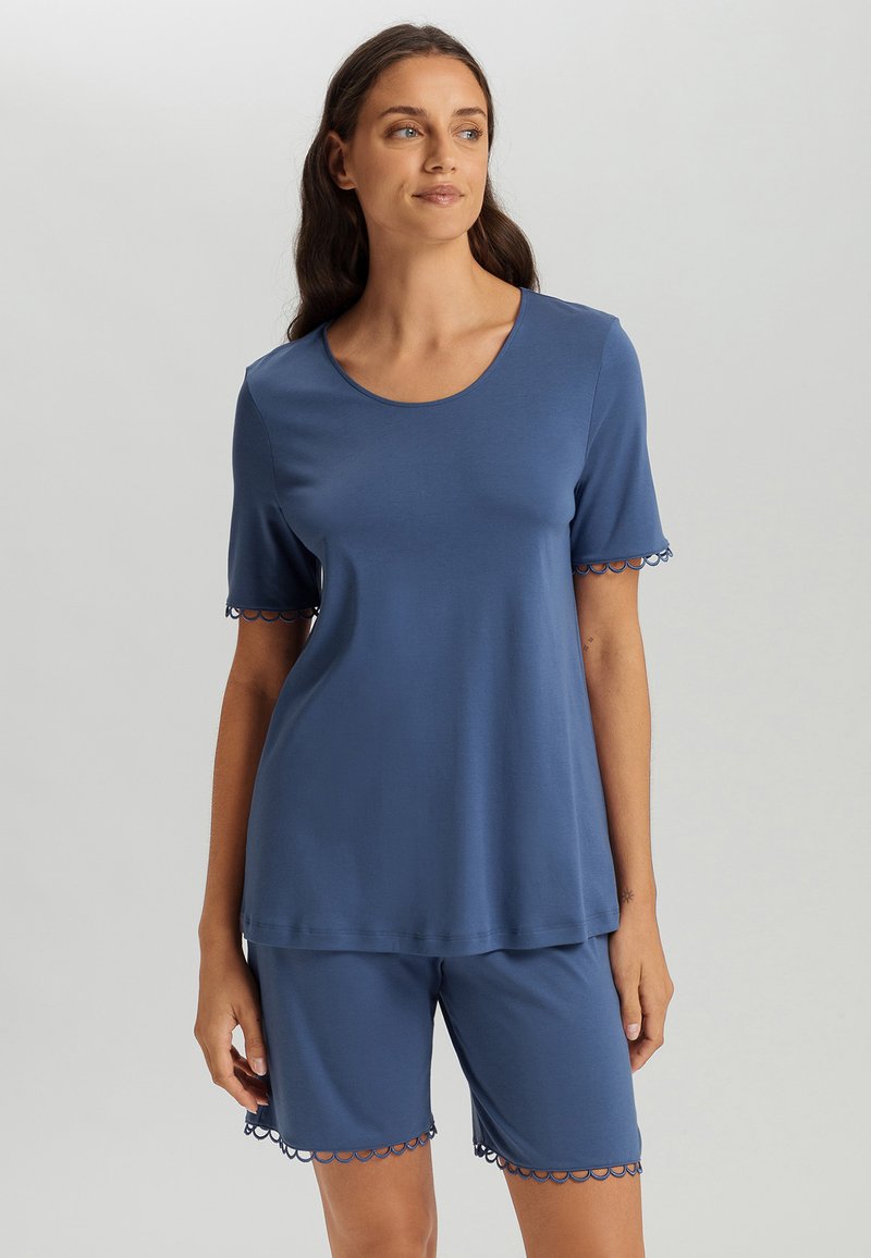 El conjunto de pijama azul cuenta con una camiseta de manga corta con un escote redondo y un acabado decorativo en forma de ondas en las mangas y en los pantalones cortos. Textura de tejido suave.
