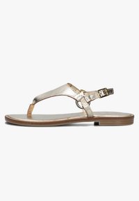 Metallisch gouden teensandalen met een cirkelvormige ringdetail, verstelbare enkelband, platte zool en een gladde leren textuur.