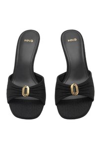 Sandali neri con fibbia in metallo dorato e una larga fascia in tessuto. La suola è piatta e presenta una superficie testurizzata.