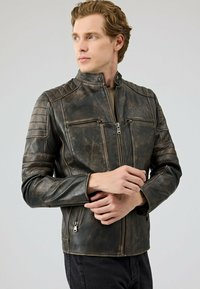 Zwarte versleten leren motorjack met gestikte schouderaccenten, ritszakken en een ontwerp met hoge kraag.