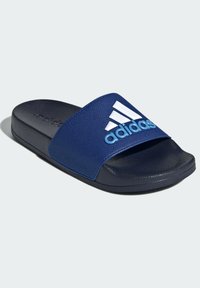 Chancla de color azul marino con una correa de tela texturizada que presenta un gran logo de Adidas en blanco y azul claro, suela de goma negra suave.