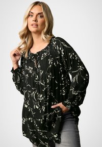 Camicia nera con stampa floreale, maniche lunghe, scollatura arricciata e dettaglio con nodo. Tessuto leggero con accenti testurizzati e motivi floreali.