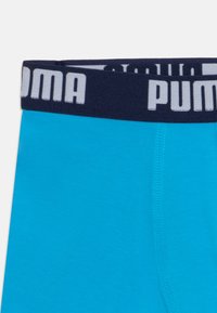 Blaue Boxershorts aus weichem Stoff mit einem marineblauen Bund und weißem "PUMA"-Logo. Glatte Textur und enganliegendes Design.