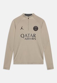 Pulóver beige de manga larga con cuello de cremallera, que presenta el logotipo negro del Paris Saint-Germain, el emblema de Jumpman y el texto "QATAR AIRWAYS" en la parte frontal.