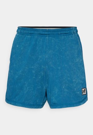 Shorts en sweat bleu avec une finition délavée. Taille élastique avec un bord noir. Présente un petit patch de logo en bas à droite.