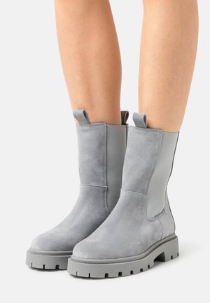 Gray suede ankle boots with elastic side panels and pull tabs, featuring a rugged sole with visible traction pattern for grip.