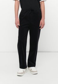 Schwarze Cordhosen mit elastischem Bund und verstellbarem Kordelzug. Gerades Bein Design, glatte Textur und dezenten Glanz.