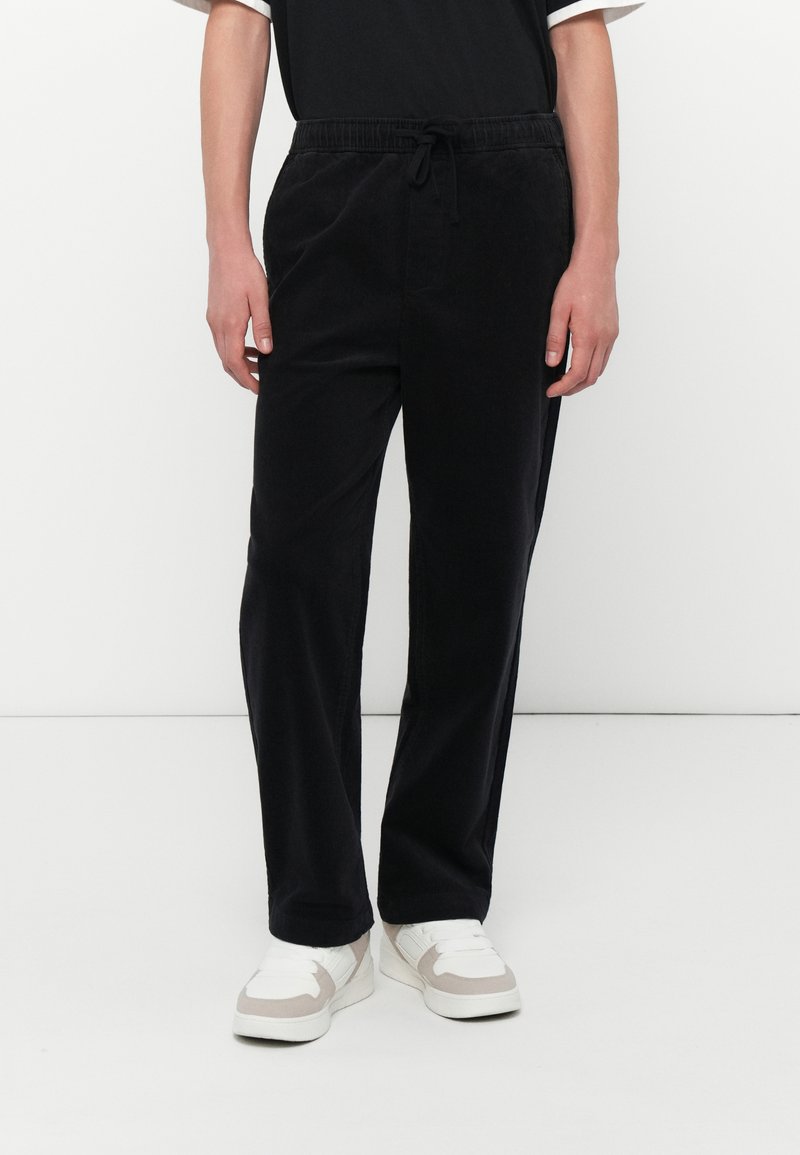 Schwarze Cordhosen mit elastischem Bund und verstellbarem Kordelzug. Gerades Bein Design, glatte Textur und dezenten Glanz.