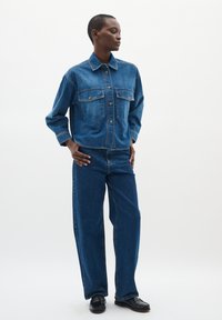 Set di giacca e pantaloni in denim di blu medio, con due tasche sul petto, chiusura a bottoni e una vestibilità comoda con design dritto.