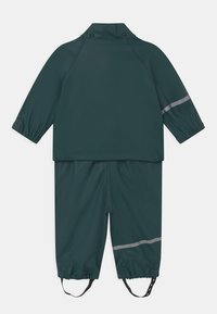 Nepremokavý dvojdielny outfit tmavozelenej farby, obsahujúci bundu s vysokým golierom a elastickými manžetami, ako aj zladené nohavice s reflexnými akcentmi.