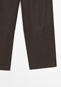 Bruine recht gesneden broek met zichtbare naaddetail bij de knieën en een iets ingekorte lengte tegen een witte achtergrond.