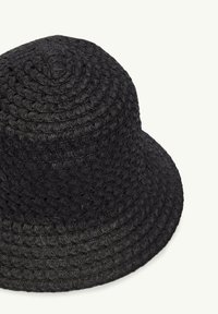 Black woven bucket hat with a rounded crown and wide brim. Made of straw-like material, featuring a textured surface and circular patterns.