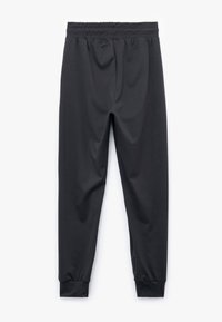 Black athletic pants made of smooth fabric, featuring an elastic waistband and tapered leg design with fitted cuffs at the ankles.