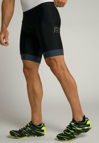 Sort sportsshorts med en grå talje og detaljer, der har en tætsiddende pasform. Bæres med sorte og neongrønne sportssko.