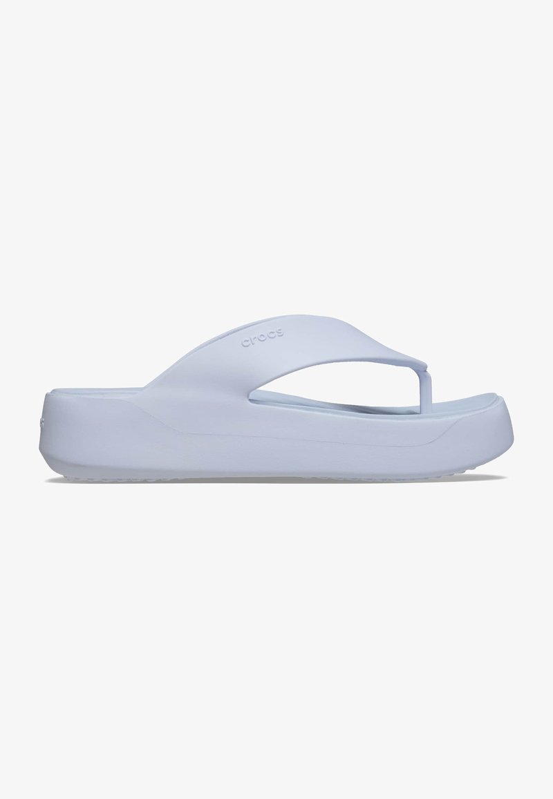 Witte rubberen slippers met een hoog platform, een T-vormig ontwerp van de bandjes en een gestructureerde zool voor grip. Minimale branding zichtbaar.
