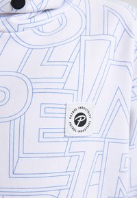 Witte sweatshirt met blauw geometrisch lettertype patroon, met een logo patch met de tekst "Petrol Industries" aan de onderkant aan de linkerzijde.