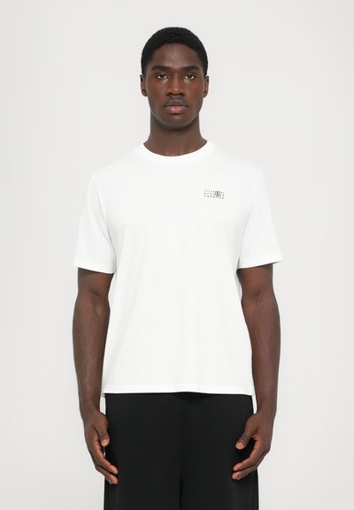 Witte katoenen t-shirt met een ronde halslijn, korte mouwen en een klein gedrukt ontwerp op de linkerborst. Rechte zoom en losse pasvorm.