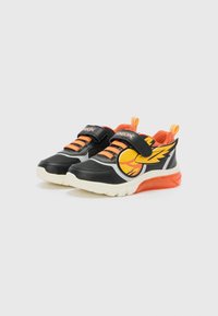 Zwarte sportschoenen met oranje accenten, klittenbandsluiting, vlamontwerp en lichte zool. Heeft ademend mesh en rubberen buitenzool.