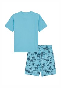 Ljusblå bomulls-T-shirt kombinerad med blå shorts som har mönster av svarta palmer och segelbåtar. Shortsens midja är av elastiskt material.