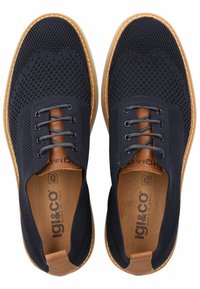 Sneakers a rete blu navy con tacco in pelle marrone, lacci grigi e suole in gomma bianca. Presentano una tomaia testurizzata e un logo all'interno.