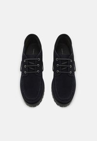 Zapatos de ante azul marino con puntera redondeada, costuras en contraste y seis ojales. Suela de goma texturizada para mayor tracción.