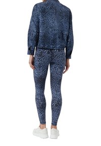Blue leopard print athletic ensemble featuring a long-sleeve top and fitted leggings, made of stretchy fabric, paired with white sneakers.