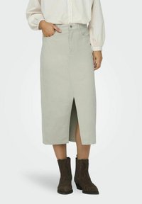 Lichtgrijze midi-rok met een voorsplit, gemaakt van katoen. Ontworpen met zakken en een knoopsluiting in de taille. Draagt bij bruin enkellaarsjes.
