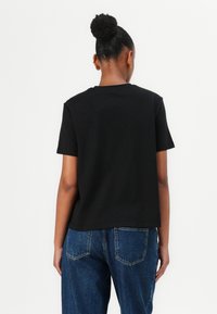 Svart bomull T-skjorte med avslappet passform, kortermede ermer og rund hals, kombinert med høyt liv blå denim jeans.