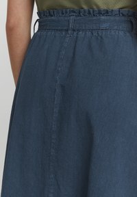 Jupe bleu marine avec une finition texturée, dotée d'une taille froncée avec un bande élastique et d'un tombé en tissu lisse.