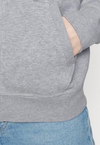 Sudadera gris con bolsillo canguro, puños y dobladillo acanalados. Confeccionada en un tejido texturizado con un acabado suave, adecuada para un look casual.