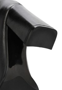 Bracciolo di una sedia in pelle nera con una texture liscia, forma leggermente arrotondata e finitura lucida. Presenta linee pulite e un design solido e robusto.