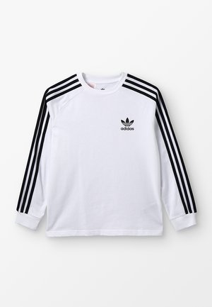 Chemise blanche à manches longues Adidas avec un design à trois bandes noires sur les manches et le logo Adidas sur le côté gauche de la poitrine.