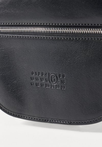 Borsa nera in pelle con finitura strutturata, dotata di una cerniera argentata e numeri in rilievo sulla parte frontale, che aggiungono un tocco di funzionalità.
