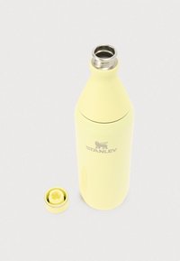 Bouteille isolante Stanley jaune avec large ouverture et bouchon à vis retiré, présentée sur fond blanc.