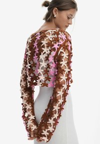 Gilet court au crochet avec des motifs floraux marron, rose et beige ; manches longues ; design ouvert ; fil texturé.