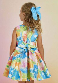 Abito floreale a linea A con stampa multicolore in tonalità pastello. Presenta un grande fiocco sul retro e una finitura in tessuto liscia e lucida.