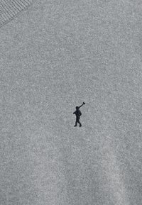 Grå tröja av stickat tyg med en liten, mörk broderad logotyp föreställande en figur med en polo-maljett på vänstra bröstet.