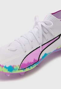 White soccer cleat with a textured upper, featuring colored accents in pink, blue, and green. Includes a black design line and laces.
